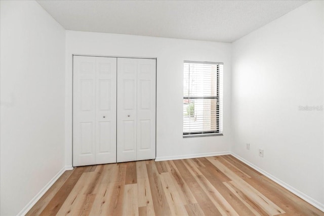 unfurnished bedroom featuring a closet, a textured ceiling, and light hardwood / wood-style flooring