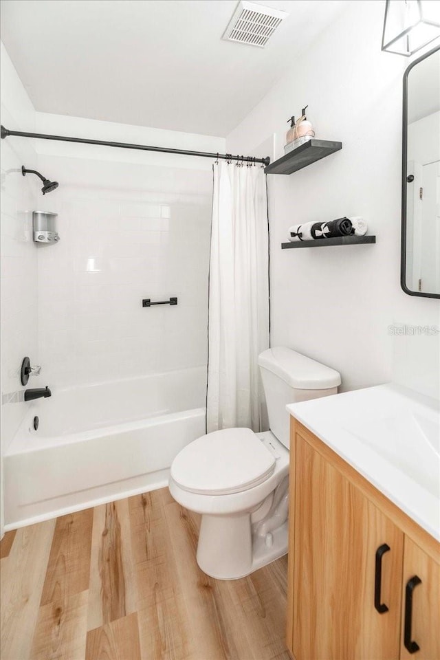 full bathroom with hardwood / wood-style floors, vanity, shower / tub combo, and toilet