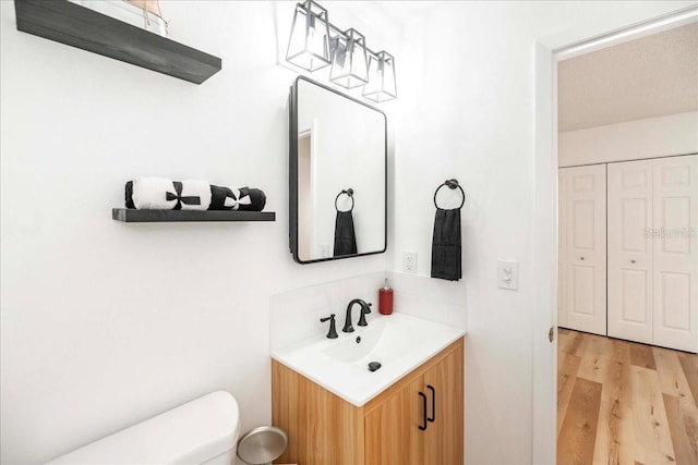 bathroom with wood-type flooring, vanity, a textured ceiling, and toilet