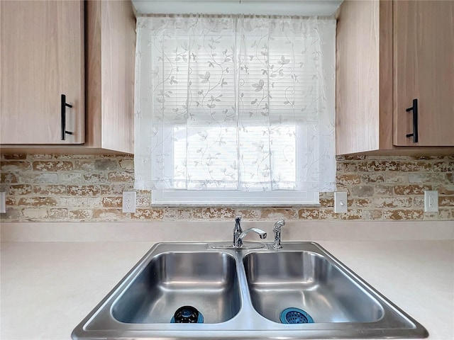 room details featuring decorative backsplash, light brown cabinetry, and sink