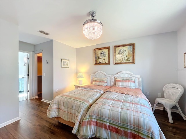 bedroom with a chandelier and dark wood-type flooring