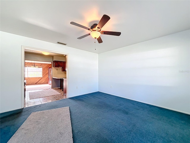 unfurnished room with carpet flooring, ceiling fan, and wood walls