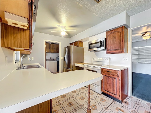 kitchen with washer and dryer, sink, stainless steel appliances, and a textured ceiling