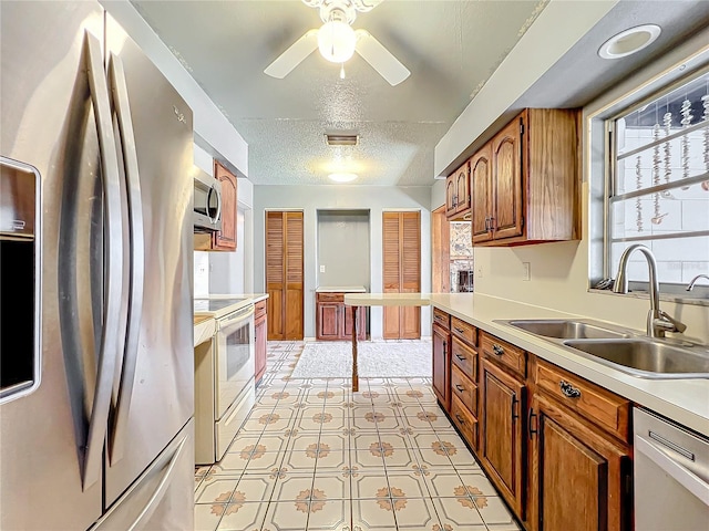 kitchen featuring ceiling fan, sink, stainless steel appliances, and a textured ceiling