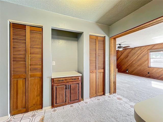 hallway with wood walls, light carpet, and a textured ceiling