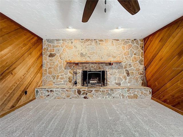 unfurnished living room featuring wooden walls, a fireplace, carpet floors, and ceiling fan