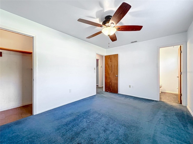 unfurnished bedroom featuring ceiling fan, dark carpet, ensuite bath, and a closet