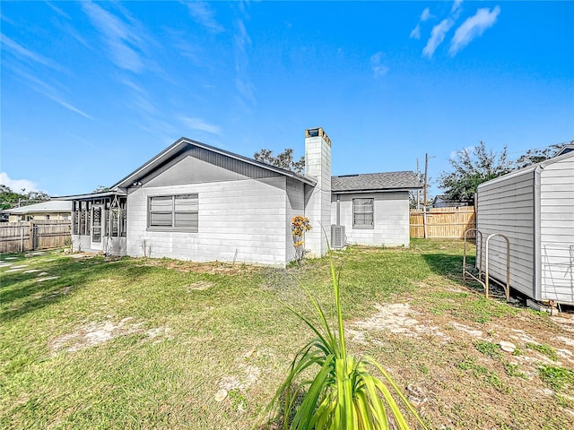 rear view of house with central AC and a yard