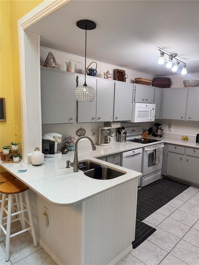 kitchen with pendant lighting, kitchen peninsula, white appliances, and sink