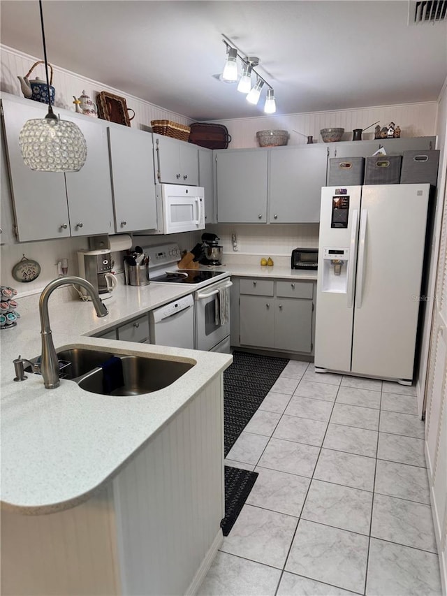 kitchen with kitchen peninsula, white appliances, sink, light tile patterned floors, and hanging light fixtures