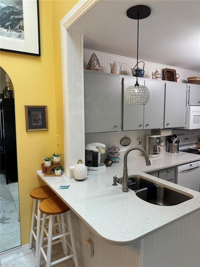 kitchen with kitchen peninsula, sink, decorative light fixtures, and white appliances