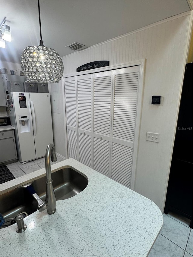 kitchen with white refrigerator with ice dispenser, sink, light tile patterned floors, decorative light fixtures, and a chandelier