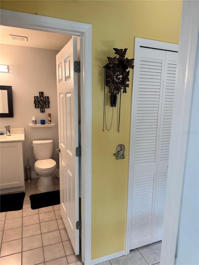 bathroom with toilet, vanity, and tile patterned floors