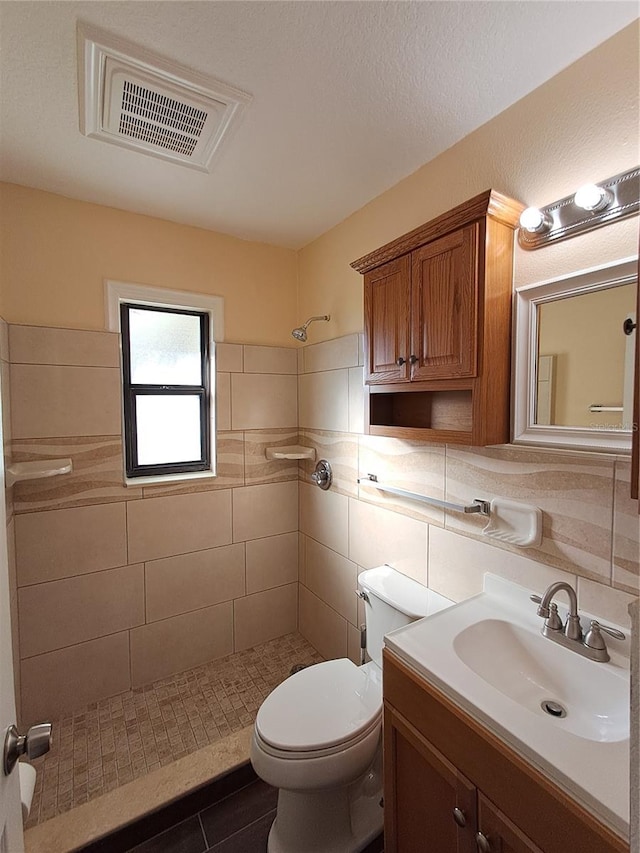 bathroom with walk in shower, vanity, tile walls, tile patterned flooring, and toilet