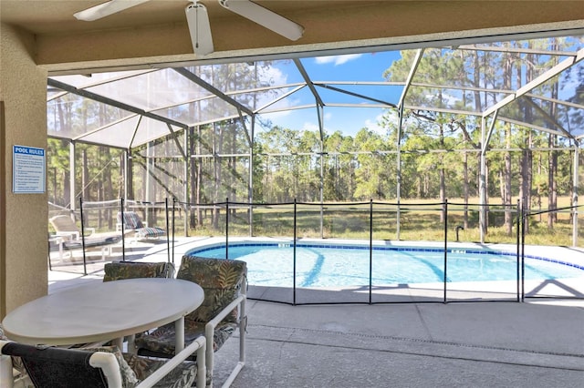 view of pool with a patio area, ceiling fan, and glass enclosure