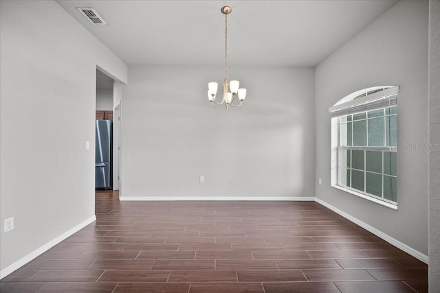 empty room featuring an inviting chandelier and dark wood-type flooring