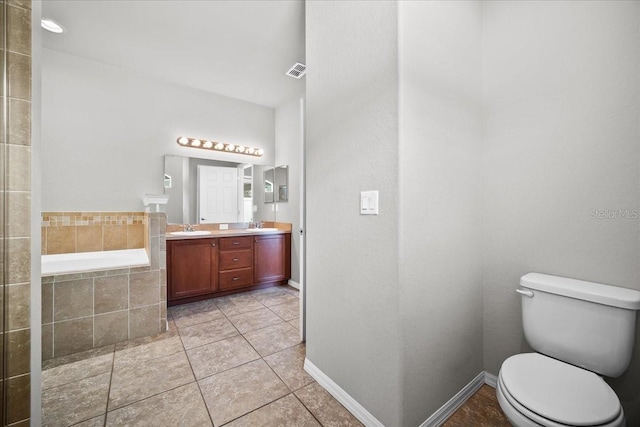 bathroom with vanity, toilet, tile patterned flooring, and tiled tub