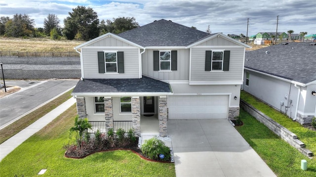 view of front of home with covered porch, a garage, and a front yard