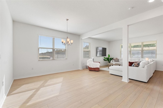 living room with a notable chandelier, light hardwood / wood-style floors, and a textured ceiling