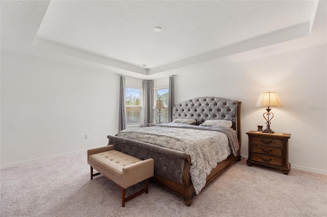 carpeted bedroom featuring a textured ceiling and a raised ceiling