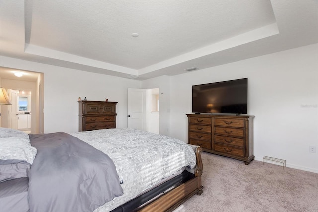 carpeted bedroom with a textured ceiling and a tray ceiling