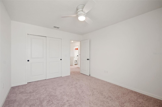 unfurnished bedroom featuring ceiling fan, light colored carpet, and a closet