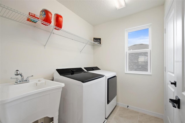 laundry area with sink, light tile patterned flooring, a textured ceiling, and independent washer and dryer