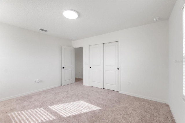 unfurnished bedroom with light carpet and a closet