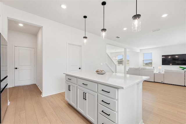 kitchen with pendant lighting, a center island, white cabinetry, and light hardwood / wood-style flooring