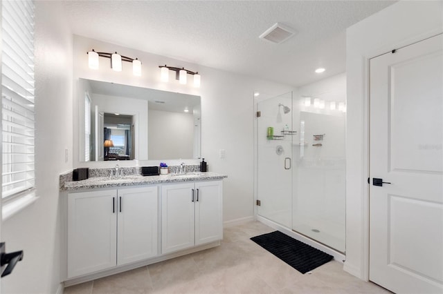 bathroom with vanity, a shower with shower door, and a textured ceiling