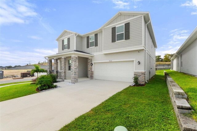 9660 Westside Hills Dr, Davenport, FL 33896 - view of front facade featuring board and batten siding, stone siding, a front lawn, and an attached garage