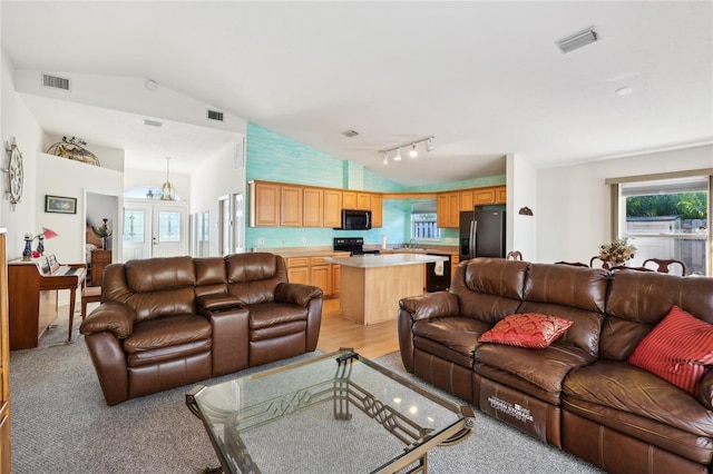 living room featuring track lighting, vaulted ceiling, and light colored carpet