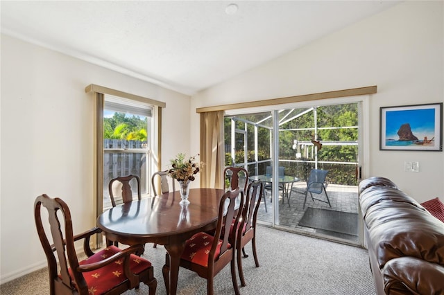 carpeted dining room with lofted ceiling