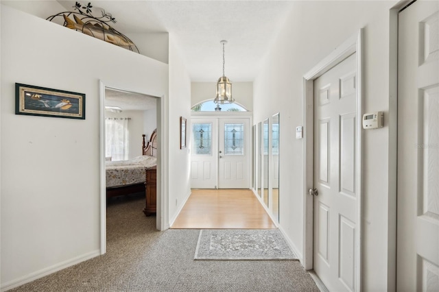 foyer entrance with carpet, a healthy amount of sunlight, and a notable chandelier