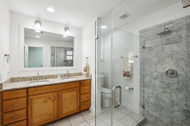 bathroom with tile patterned floors, vanity, a shower with shower door, and toilet