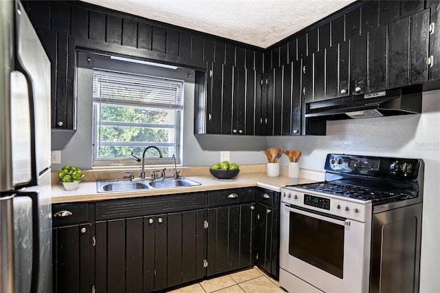 kitchen with sink, light tile patterned floors, stainless steel appliances, and a textured ceiling