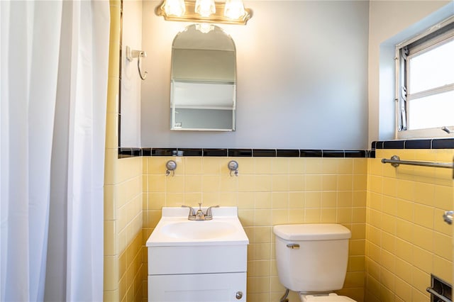 bathroom with vanity, toilet, and tile walls