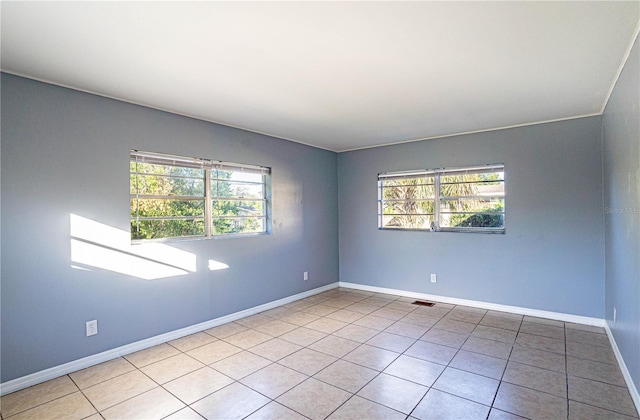 tiled spare room featuring a healthy amount of sunlight