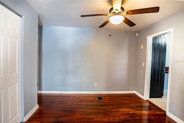 empty room with ceiling fan and dark hardwood / wood-style flooring