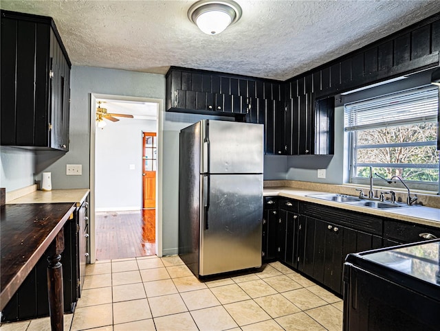 kitchen featuring stainless steel fridge, a textured ceiling, ceiling fan, sink, and light tile patterned floors