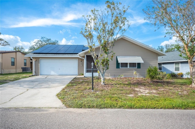 ranch-style house featuring central AC unit, solar panels, and a garage