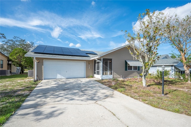 single story home with solar panels, cooling unit, a sunroom, a front yard, and a garage