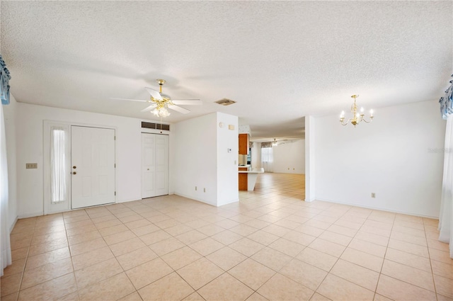 unfurnished room with ceiling fan with notable chandelier, light tile patterned floors, and a textured ceiling