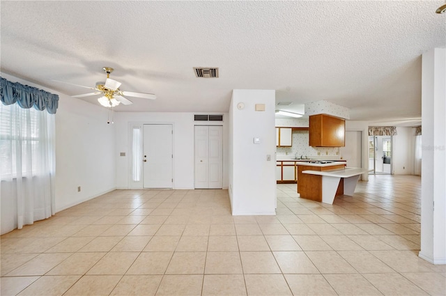 kitchen featuring ceiling fan, a healthy amount of sunlight, decorative backsplash, and light tile patterned floors