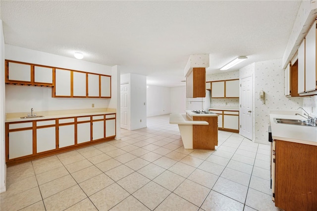 kitchen with a textured ceiling, a center island, light tile patterned floors, and sink