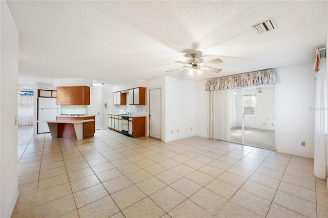 unfurnished living room with plenty of natural light, ceiling fan, light tile patterned floors, and sink