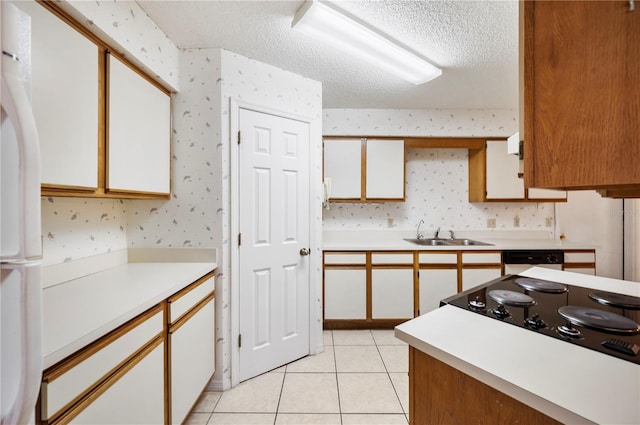 kitchen with a textured ceiling, sink, white refrigerator, white cabinetry, and light tile patterned flooring