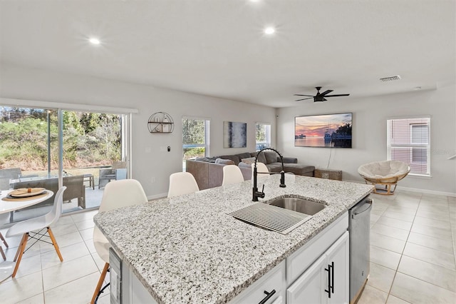 kitchen featuring a breakfast bar, a center island with sink, sink, ceiling fan, and white cabinetry