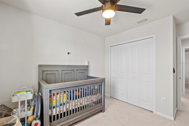 carpeted bedroom featuring ceiling fan, a closet, and a crib