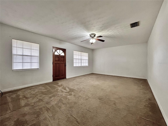 entryway featuring dark colored carpet, ceiling fan, and a textured ceiling